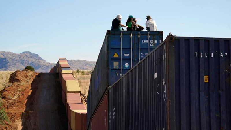 Activists sit on newly installed shipping containers along the border creating a wall between...