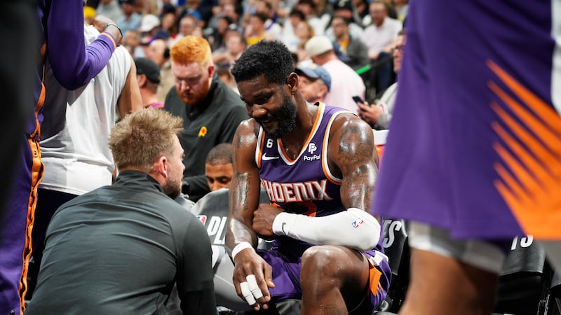 Trainer tends to Phoenix Suns center Deandre Ayton (22) after he was injured in the first half...