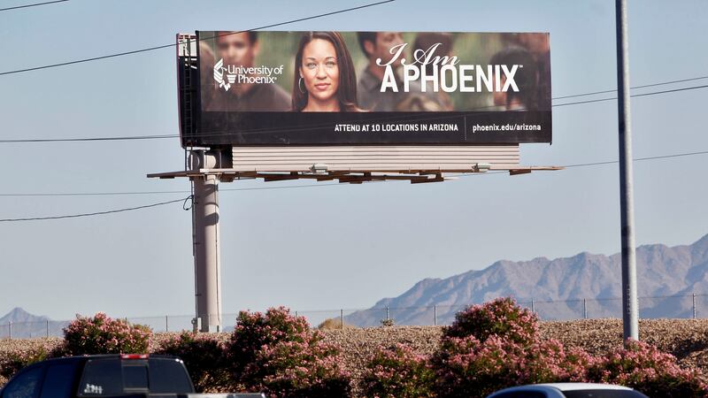 A billboard sign above an Arizona roadway promoting the University of Phoenix campuses in...
