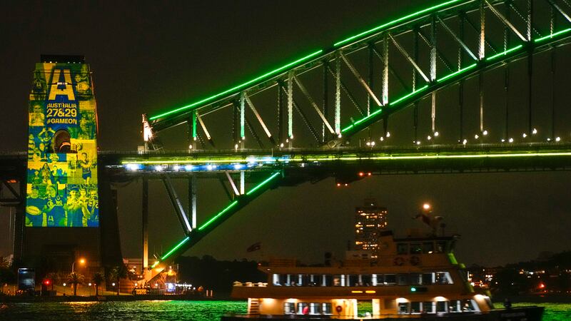 A Sydney ferry sails past the illuminated pylon of the Sydney Harbour Bridge ahead of the...
