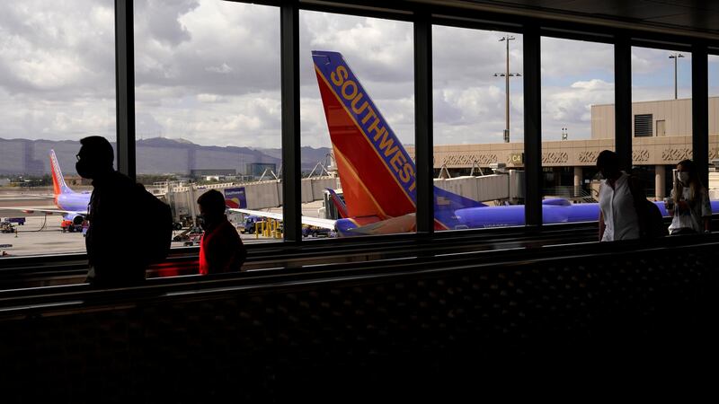 FILE - In this March 26, 2021 file photo, passengers walk past a Southwest Airlines plane at...