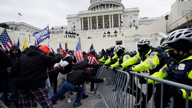 FILE - Rioters loyal to President Donald Trump try to break through a police barrier Jan. 6,...