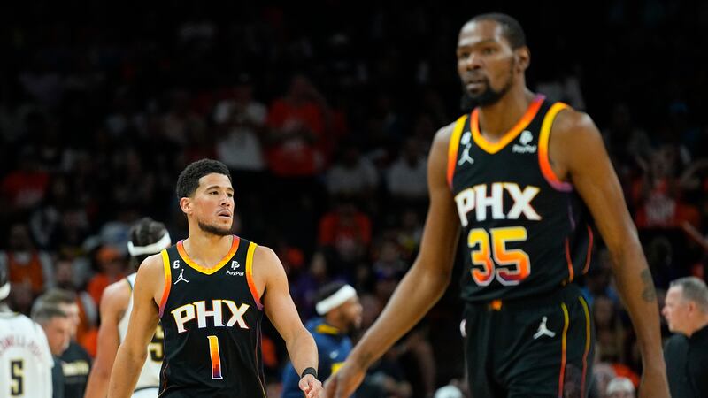 Phoenix Suns guard Devin Booker (1) and forward Kevin Durant (35) walk to their bench during...