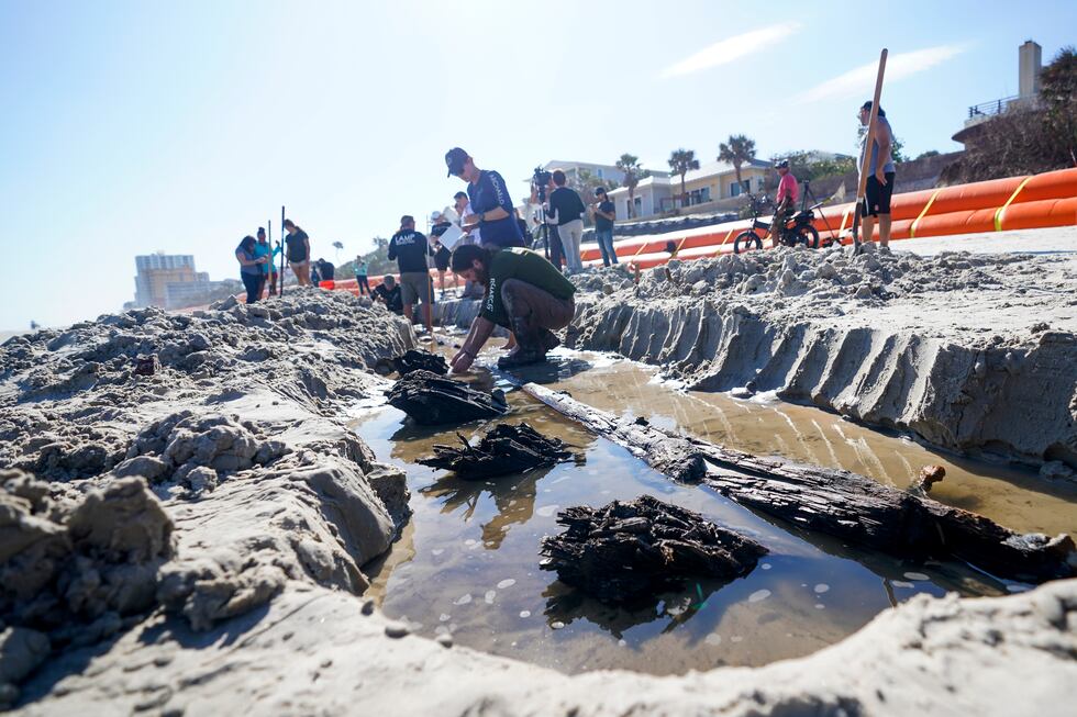 Members of a team of archaeologists study a wooden structure in the sand, Tuesday, Dec. 6,...