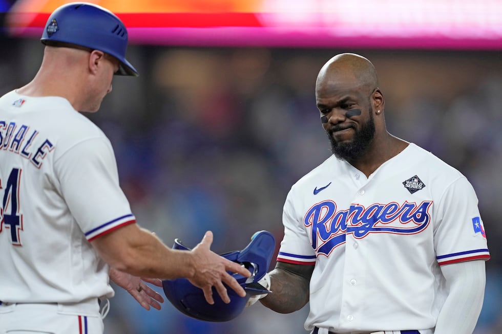 Texas Rangers' Adolis Garcia, right, hands his helmet to first base coach Corey Ragsdale after...