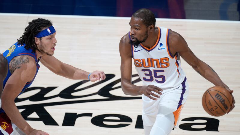 Phoenix Suns forward Kevin Durant, right, looks to drive the lane as Denver Nuggets forward...