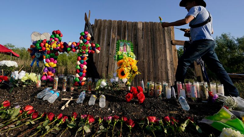 FILE - Roberto Marquez, of Dallas, adds a flower to a makeshift memorial at the site where...